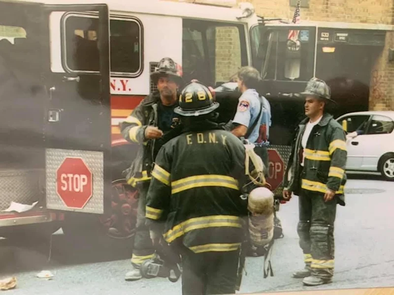 An archival photograph of firefighters beside an FDNY apparatus.